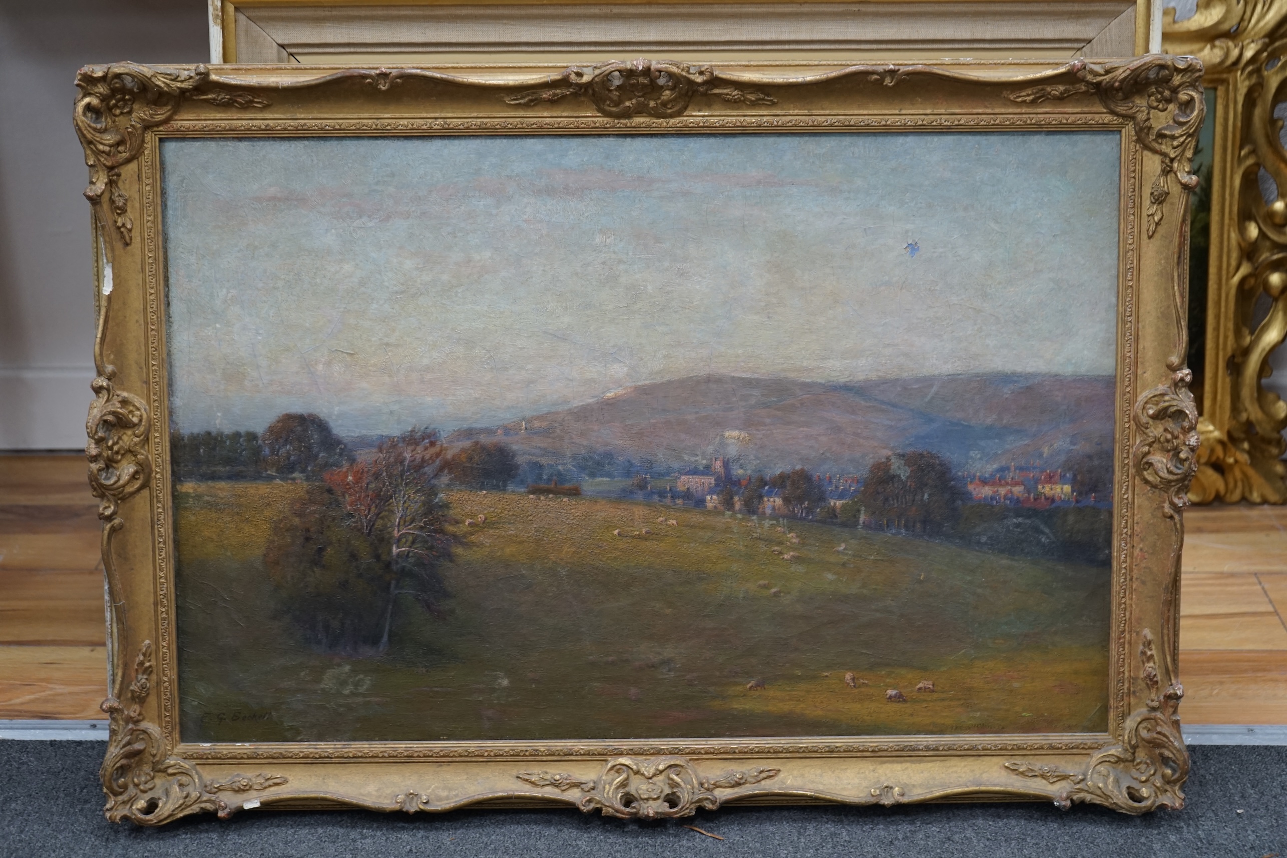 E G Beckett, oil on canvas, Extensive landscape with town before hills, signed, 48 x 75cm, ornate gilt framed. Condition - poor